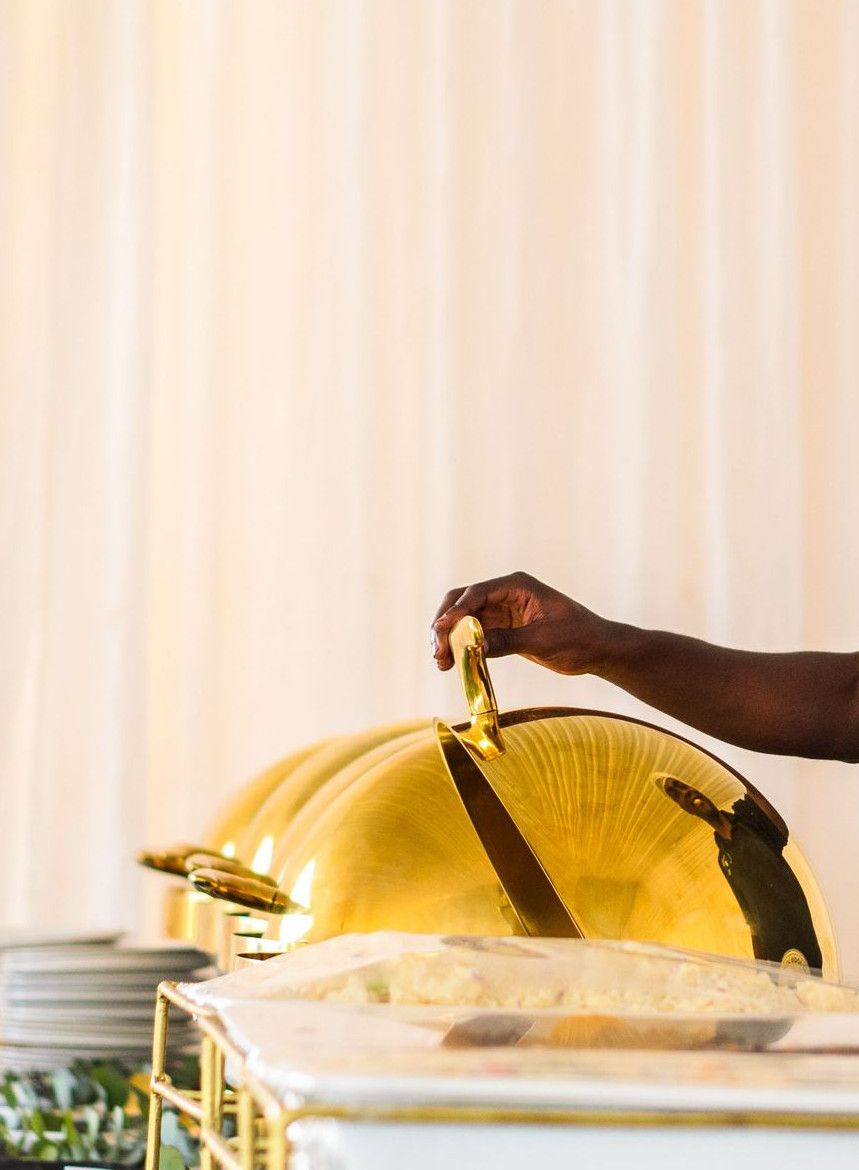 A cheerful caterer serves food at a buffet, showcasing professional catering service.